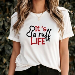 Könnte beinhalten: Weißes T-Shirt mit einer schwarzen und roten Grafik, auf der "It's a ruff life" mit einem Knochen-Motiv steht.
