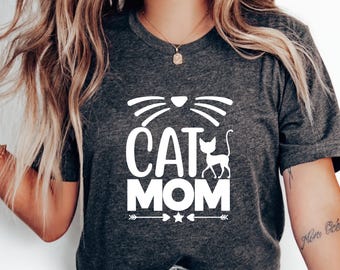 May include: A gray t-shirt with the text "CAT MOM" in white, featuring a stylized cat silhouette and cat whiskers.