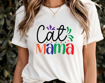 May include: White t-shirt with the text "Cat Mama" in a colorful design. The word "Cat" is in black script, and "Mama" is in orange, blue, green, and red. The shirt has rolled-up sleeves.