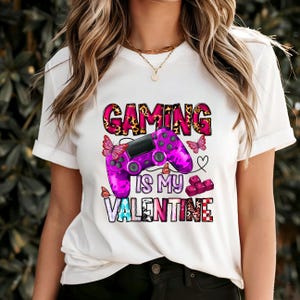 May include: White t-shirt with a pink and purple video game controller graphic and the text "Gaming is my Valentine".