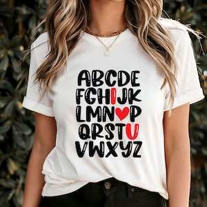 Camiseta com alfabeto romântico, estampa de letras de amor, design de símbolo de coração, presente exclusivo para o dia dos namorados, camiseta fofa com tipografia, vestuário moderno para o amor