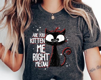 Puede incluir: Una camiseta gris oscuro con una ilustración de un gato negro y el texto "Are you kitten me right meow" en rojo.