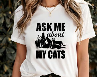 Może przedstawiać: Biała koszulka z czarnym napisem "Ask me about my cats". Napis jest przetarty, a wokół niego znajdują się czarne sylwetki kotów.