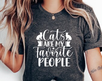 May include: A gray t-shirt with a white graphic that says "Cats are my favorite people". The graphic also includes two stylized cats.