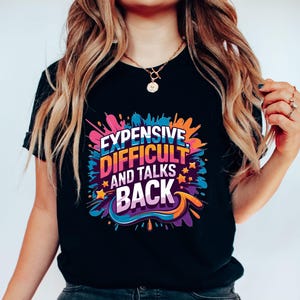 May include: Black t-shirt with a colourful graphic that says "Expensive, Difficult and Talks Back".