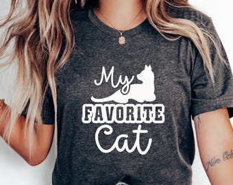 May include: Dark gray t-shirt with the text "My FAVORITE Cat" in white, along with a white cat silhouette. The shirt is a crew neck and appears to be made of a soft material.