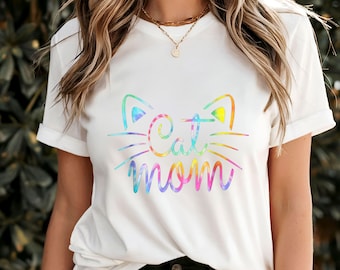 May include: White t-shirt with a rainbow tie-dye design of a cat face and the words "Cat Mom".