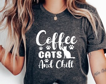 May include: A gray t-shirt with the text "Coffee Cats And Chill" in white lettering. The text is surrounded by paw prints and a cat silhouette.