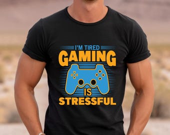 May include: Black t-shirt with a blue and orange graphic of a video game controller. The text "I'm Tired Gaming Is Stressful" is printed on the shirt.