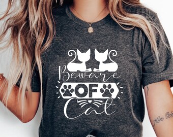 May include: A gray t-shirt with a white graphic design that says "Beware of Cat" with two cats and paw prints.