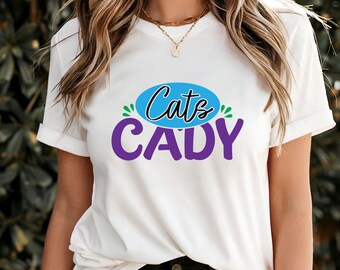 May include: White t-shirt with the text "Cats CADY" in a blue and purple design. The word "Cats" is in a blue oval with green accents. The word "CADY" is in purple.
