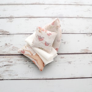 May include: A set of three decorative pillows with a floral and bird print. The pillows are made of a soft, white fabric and are perfect for adding a touch of whimsy to any room.