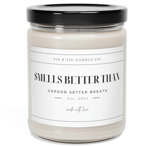 以下が含まれることがあります： 黒い蓋が付いた白いキャンドルジャー。ラベルには「FIR & FIG CANDLE CO. SMELLS BETTER THAN GORDON SETTER BREATH Est. 2023 made with love」と書いてあります