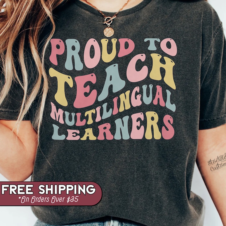 May include: A dark grey t-shirt with the text "Proud to Teach Multilingual Learners" in colorful retro font.