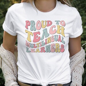 May include: White t-shirt with the text "Proud to Teach Multilingual Learners" in colorful, retro-style lettering.