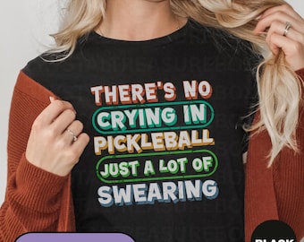 May include: Black t-shirt with the text "THERE'S NO CRYING IN PICKLEBALL JUST A LOT OF SWEARING" in colorful block letters. The shirt has a crew neck and is part of the T-SHIRTS category.