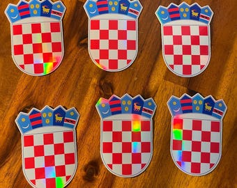 May include: Six stickers featuring the Croatian coat of arms. Each sticker has a red and white checkered shield design, topped with a blue and white crest. The stickers have a holographic effect, creating a rainbow sheen.