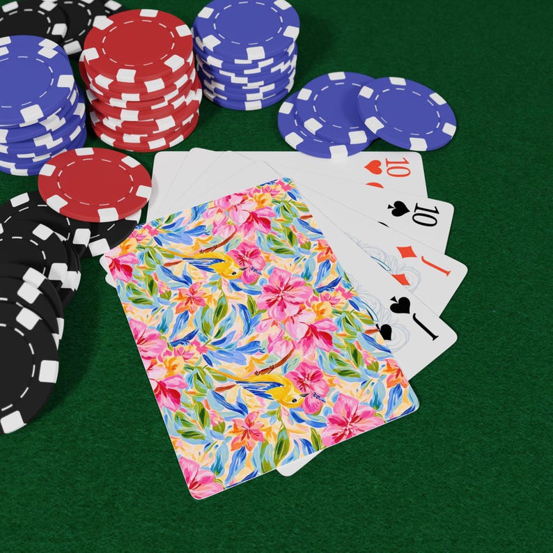 May include: Poker set with playing cards and poker chips. The playing cards have a floral design with pink, yellow, and blue flowers. The poker chips are red, blue, black, and white.