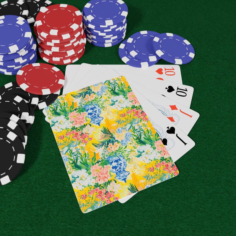 May include: Poker set with stacks of red, blue, and black chips, playing cards, and a floral patterned card. The playing cards show the number 10 in the suits of hearts, diamonds, and spades. The floral card has a yellow background.
