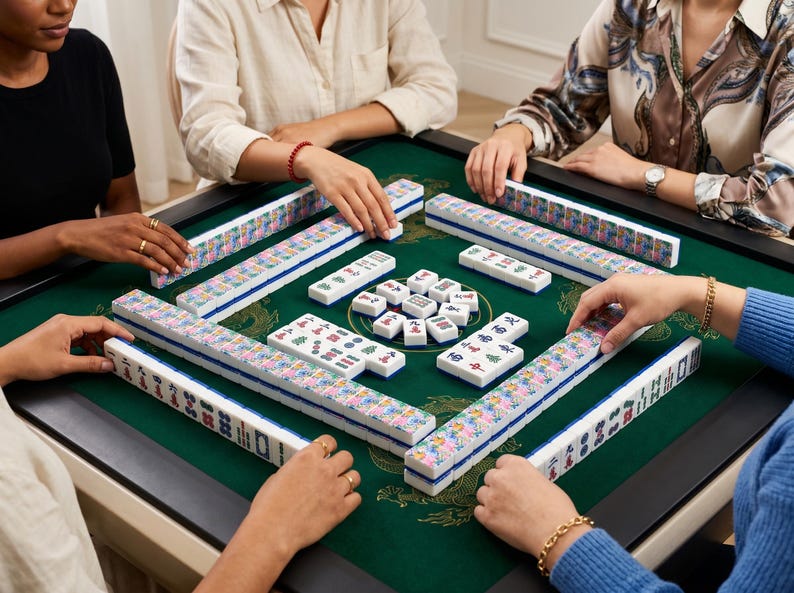May include: A group of people playing Mahjong. The game is set on a green felt table with white and blue tiles. The tiles are arranged in a square, with players' hands around the edges.