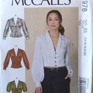 May include: McCall's M7978 sewing pattern featuring a woman wearing a cropped blouse with long sleeves and a V-neck. The pattern includes variations with different sleeve styles and colors. The size range is E5 (14-16-18-20-22).