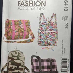 May include: A sewing pattern for four different bags. The bags are a pink floral crossbody bag, a black and white zebra print backpack, a camouflage backpack, and a pink and black plaid crossbody bag. The pattern number is M6410/OSZ 1.
