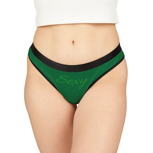 May include: Green thong underwear with a black trim and the word "Sexy" in a cursive font. The underwear is made of a soft material.