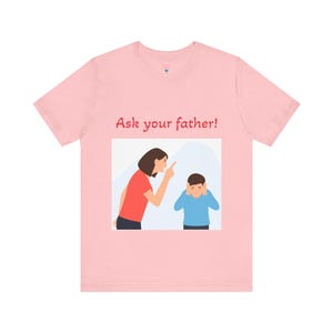 May include: A light pink t-shirt featuring the text "Ask your father!" above an illustration of a woman pointing at a child covering their ears. The woman is wearing a red shirt, and the child is wearing a blue shirt.