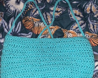 Peut inclure: Un sac en crochet turquoise avec une longue bandoulière. Le sac est réalisé avec un point simple et possède une fermeture nouée.