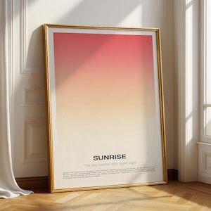 Puede incluir: Una impresión artística enmarcada con un degradado de tonos rojos, naranjas y amarillos. El marco dorado rodea la obra de arte, que presenta la palabra "SUNRISE" y la frase "The sky opens with quiet light."
