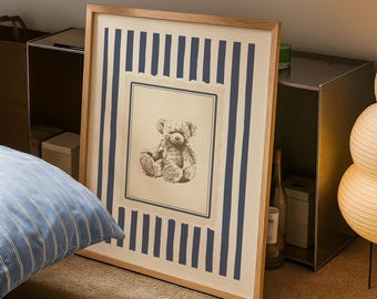 Könnte beinhalten: Ein gerahmter Druck mit einer sepiafarbenen Teddybär-Illustration. Das Kunstwerk ist von einem cremefarbenen Rahmen und marineblauen vertikalen Streifen umgeben. Der Rahmen besteht aus hellem Holz.
