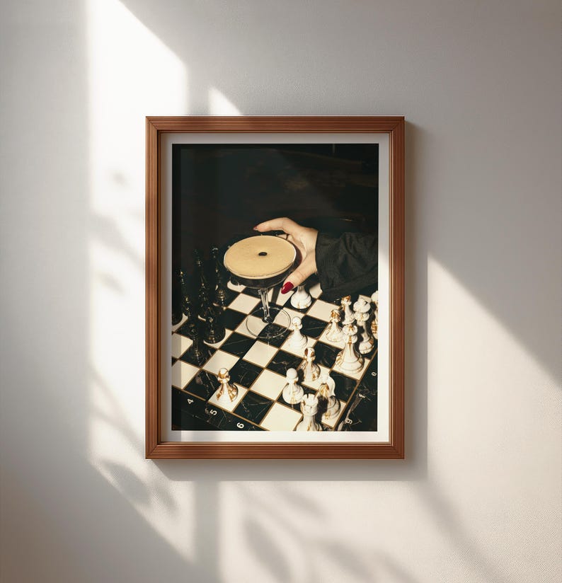 Moody photograph of a hand with red nails holding a martini over a chessboard, dramatic bar and game night themed wall art, printable decor