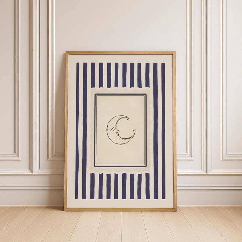 Vintage-inspired printable wall art featuring a hand-drawn crescent moon illustration with a softly smiling face, centered within a muted parchment-style frame. The moon is surrounded by layered, scalloped-edge borders and encased in deep navy vertical stripes, adding a celestial yet refined aesthetic. Styled in a minimalist, quiet luxury interior with warm wood flooring and decorative wall paneling, this digital download evokes dreamy, moody nighttime vibes.