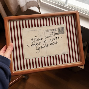 Könnte beinhalten: Eine gerahmte Postkarte mit Holzrahmen. Die Postkarte hat eine Vintage-Ästhetik mit dem Text "Your custom text or quote, lyrics here". Der Hintergrund zeigt rot-weiße vertikale Streifen.