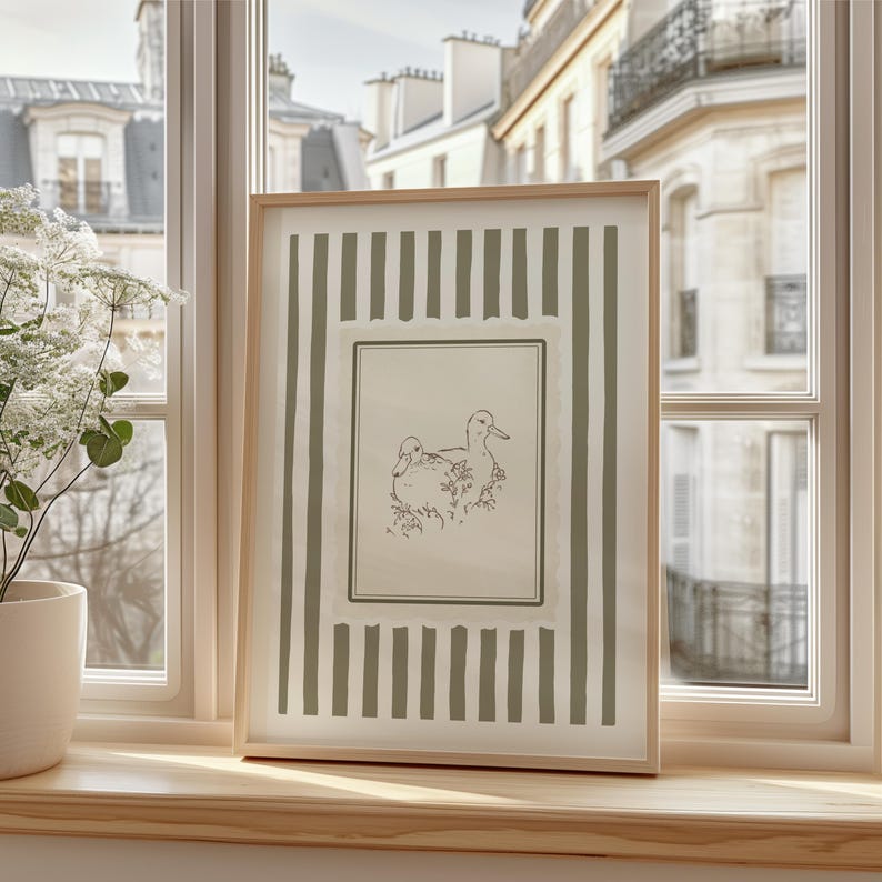 This vintage duck art print features two hand-drawn ducks among flowers, framed by soft sage stripes and a scalloped border. Ideal for cottagecore nurseries, farmhouse spaces, or elegant gallery walls, it adds gentle charm and a nature-inspired warmth to any room.