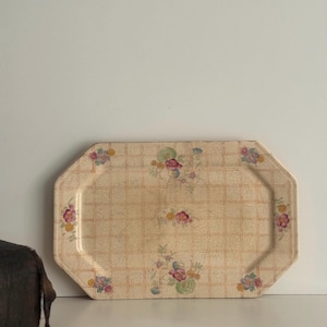 May include: An octagonal serving tray with a cream-colored background and a grid pattern. The tray is decorated with floral designs in pink, yellow, and green. The tray is likely made of ceramic or porcelain.