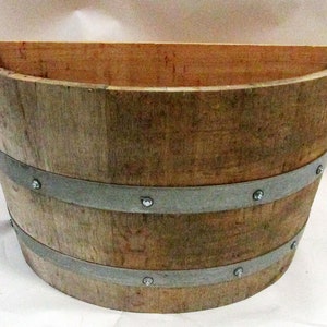 May include: Half-round wooden planter with two metal bands and decorative rivets. The planter is made of natural wood with a rustic finish.