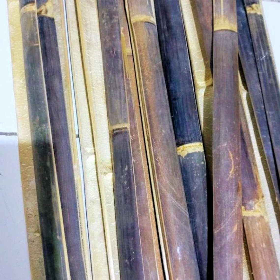 May include: A bundle of dark brown bamboo sticks, some with a lighter brown hue, arranged in a vertical pattern.