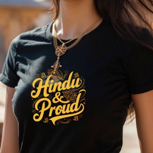 Puede incluir: Una camiseta negra con un gr&aacute;fico dorado que dice "Hindu & Proud" con un dise&ntilde;o floral y el s&iacute;mbolo Om.