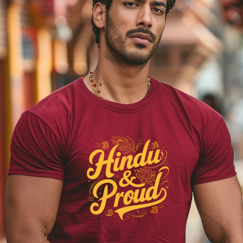 Puede incluir: Una camiseta granate con un gr&aacute;fico amarillo que dice "Hindu & Proud" con s&iacute;mbolos Om estilizados y dise&ntilde;os florales.