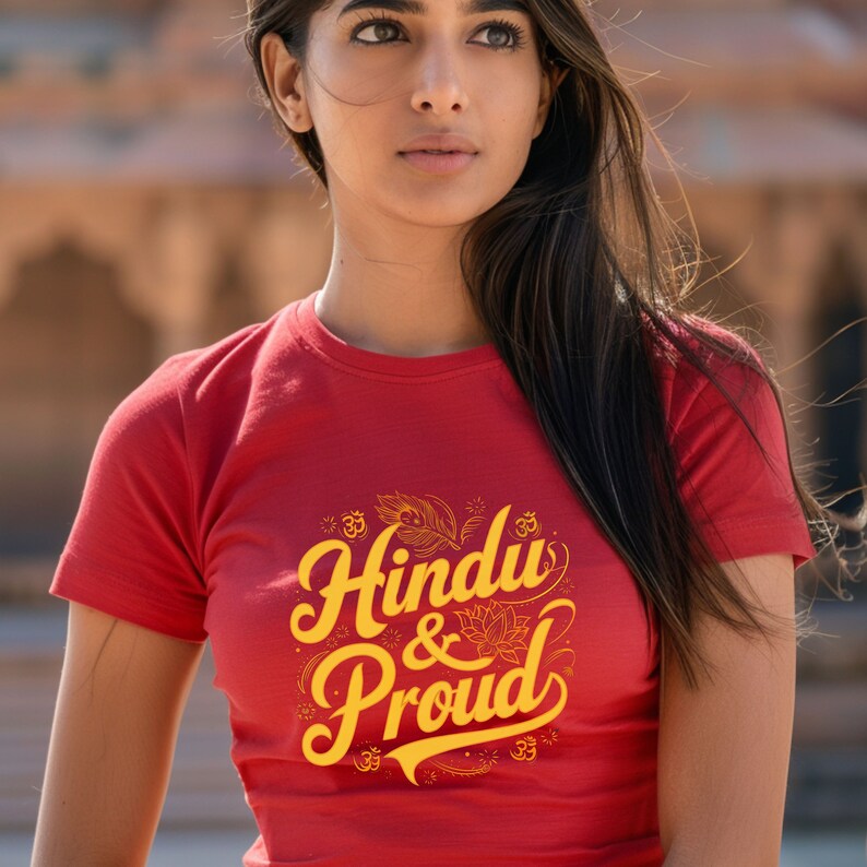 Puede incluir: Camiseta roja con un gr&aacute;fico amarillo que dice "Hindu & Proud" con un s&iacute;mbolo Om estilizado y un dise&ntilde;o de pluma.