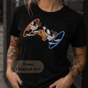 May include: A black short-sleeved t-shirt featuring a graphic print of a character moving through an orange portal and emerging from a blue portal. The design includes the text From Original Art! printed in a dark oval shape on the lower left side.