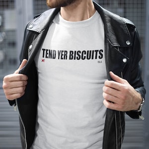 May include: White t-shirt with black text that reads "Tend Yer Biscuits" with a red "X" and the letters "T.L.L." underneath.