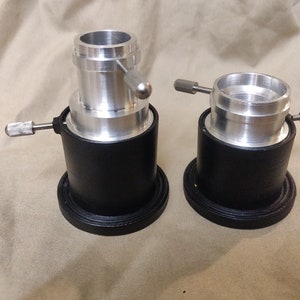 May include: Two silver telescope adapters with black bases. The adapters have a threaded ring and a knob for adjusting the fit.