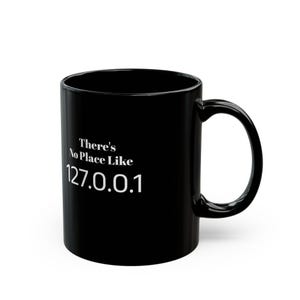Pode incluir: Caneca de café de cerâmica preta com texto branco que diz "There's No Place Like 127.0.0.1".