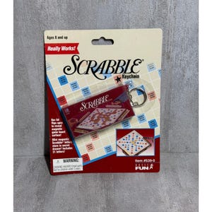 May include: Scrabble keychain on a red and white card. The keychain features a miniature Scrabble game board and includes 31 magnetic letters. The packaging reads "Really Works!" and "Ages 8 and up."