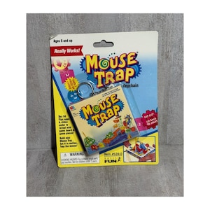 May include: A "Mouse Trap" keychain, featuring the game's logo and a miniature game board image. The packaging includes text like "Really Works!" and "Ages 8 and up." The keychain is attached to a blue and yellow card.