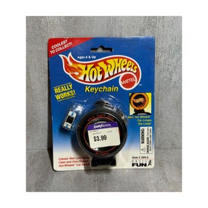 May include: A Hot Wheels keychain package with a blue and white car. The package is blue with the Hot Wheels logo and text that reads "Keychain". The package also includes the text "Coolest to Collect!" and "Really Works!"