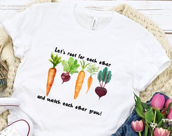 May include: White t-shirt with a graphic of carrots and beets with the text "Let's root for each other and watch each other grow!"