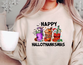 Pode incluir: Uma camisa de moletom bege com o texto "Happy Hallothanksmas" e um gráfico de três xícaras de café com tema de férias. As xícaras são decoradas com abóboras, bengalas de doces e uma caveira.